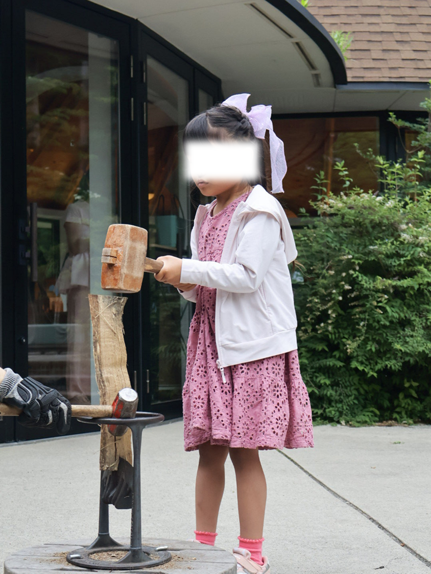 子供が専用ハンマーで薪を割る様子
