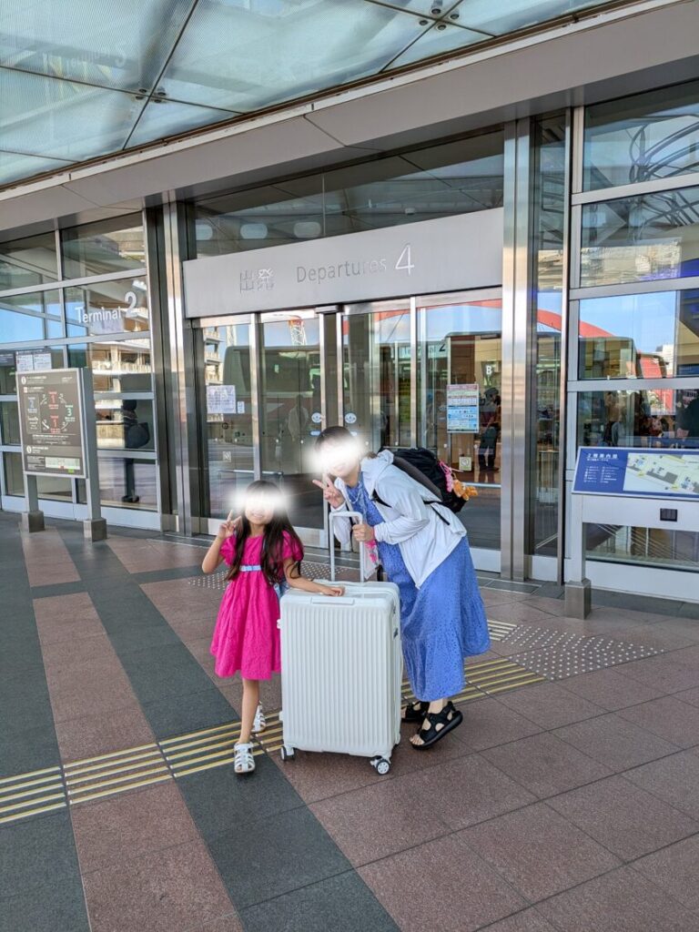 羽田空港第2ターミナルの出発ゲート前で、スーツケースと一緒に記念撮影をする親子