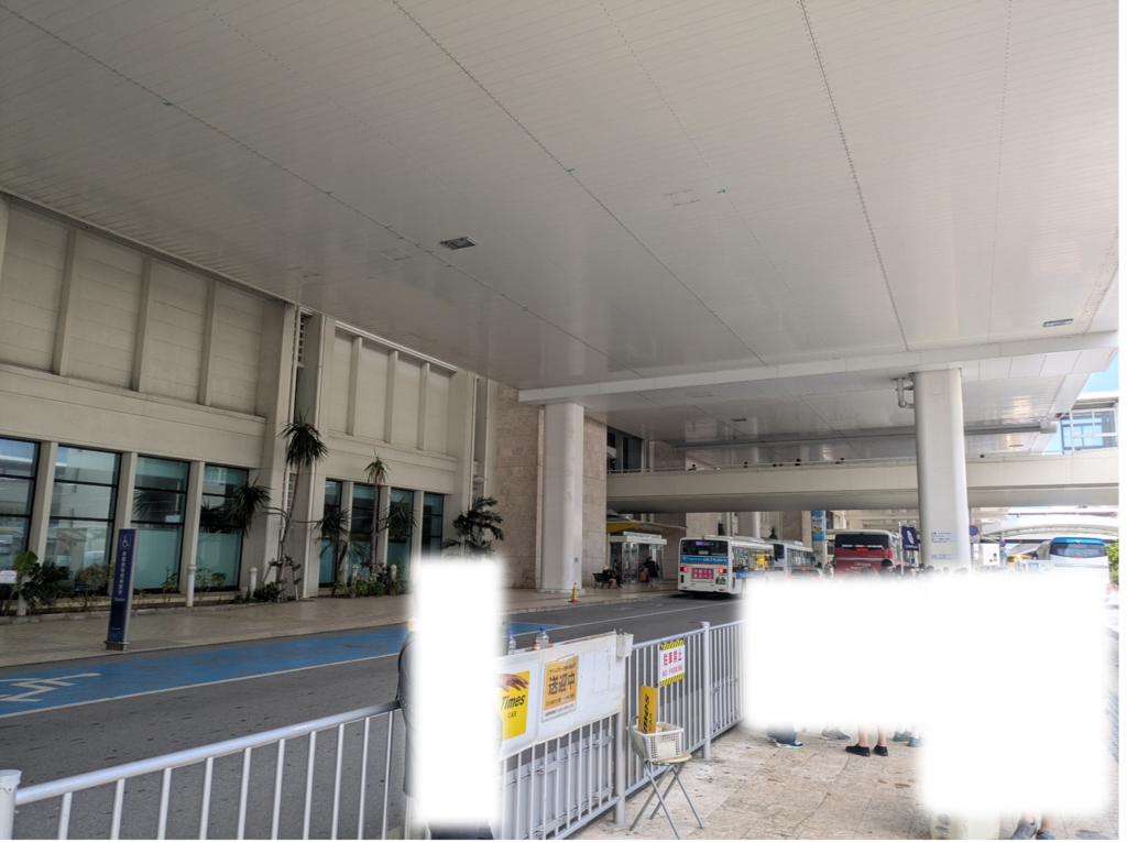 那覇空港1階の屋外にあるレンタカー送迎バス乗り場と待機列の様子