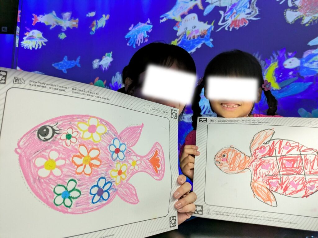 チームラボで描いた魚の絵が壁のスクリーンに映し出される体験