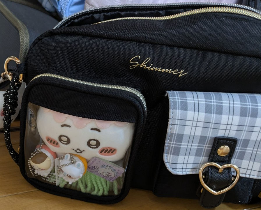 ショルダーバッグのクリアポケットに収納された、ちいかわのぬいぐるみとビッくらポンで当たったフィギュア