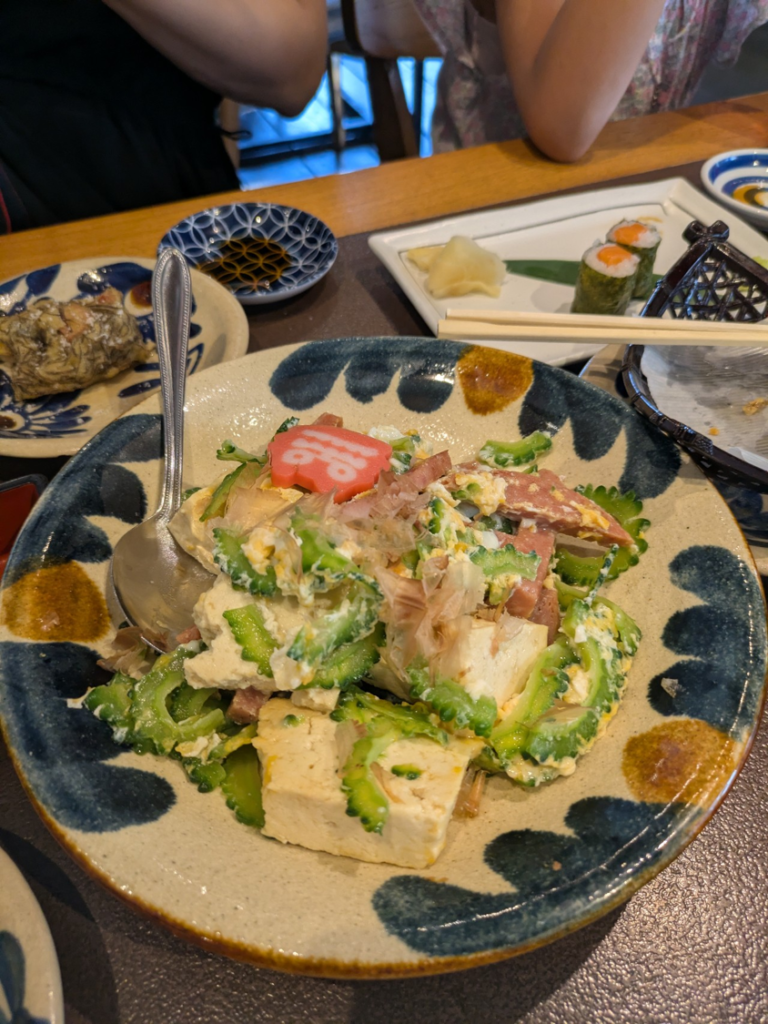 沖縄居酒屋「沖縄の台所 ぱいかじ」で、ゴーヤー、豆腐、ポーク、卵がたっぷり入ったゴーヤーちゃんぷるーの大皿料理。