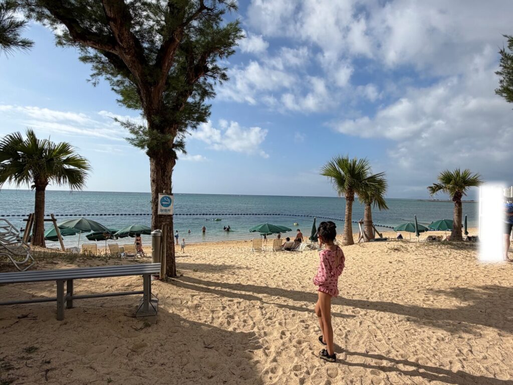 青い海と白い砂浜が広がるリゾートビーチの風景と砂浜に立つ娘
