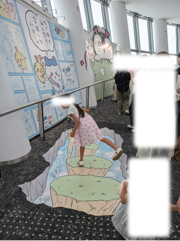 スカイツリー天望回廊の床面に描かれたちいかわのトリックアートの上で飛び跳ねるポーズをとる子ども