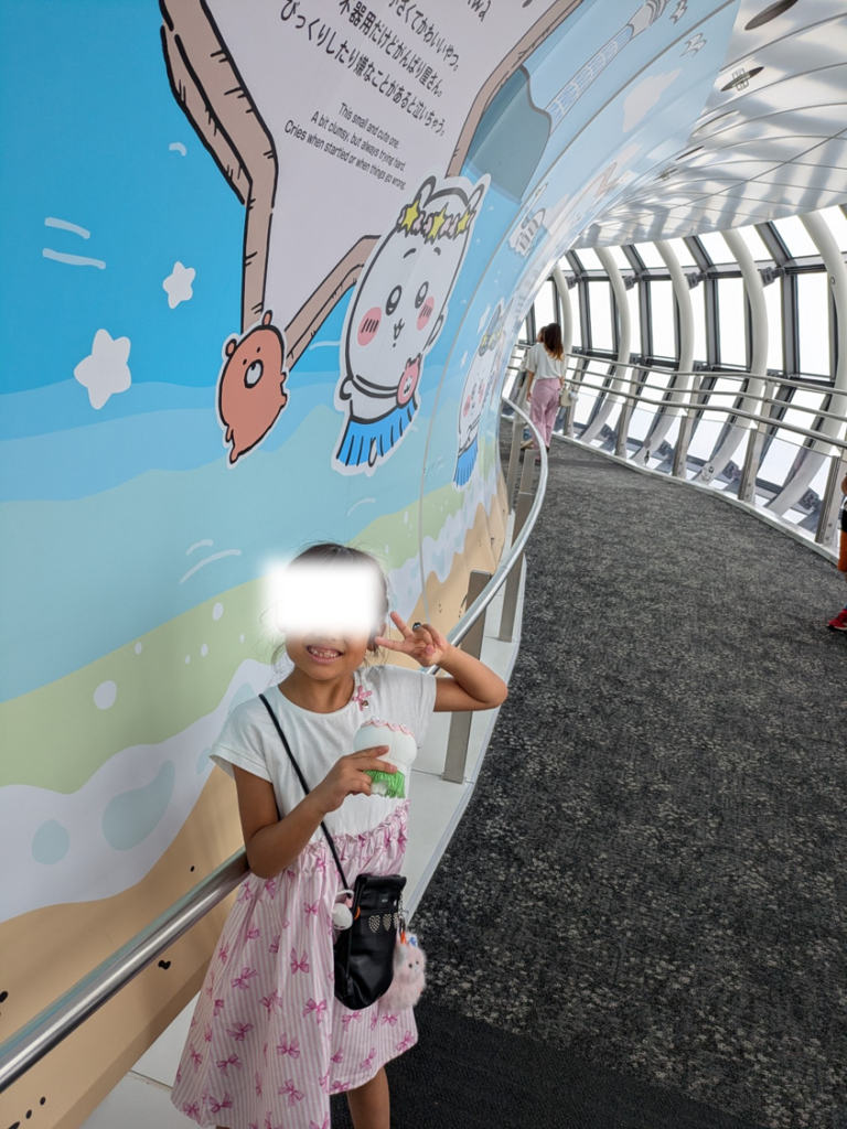 東京スカイツリー天望回廊のちいかわ特別壁面イラストの前でピースサインをする子ども