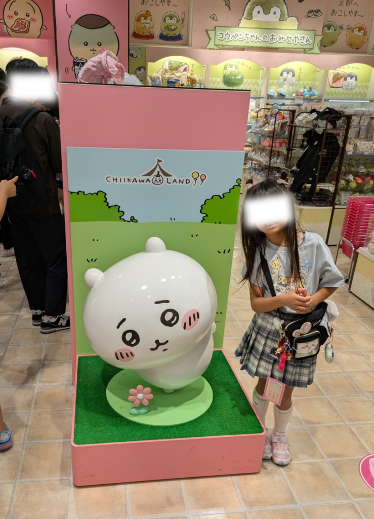 ちいかわランド京都四条河原町店の店内にある、ちいかわの可愛い立体モニュメントと記念撮影をする娘