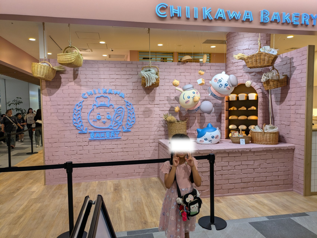 「ちいかわベーカリー」の店舗前にある可愛いディスプレイやフォトスポットの前で嬉しそうにポーズをとる娘の様子