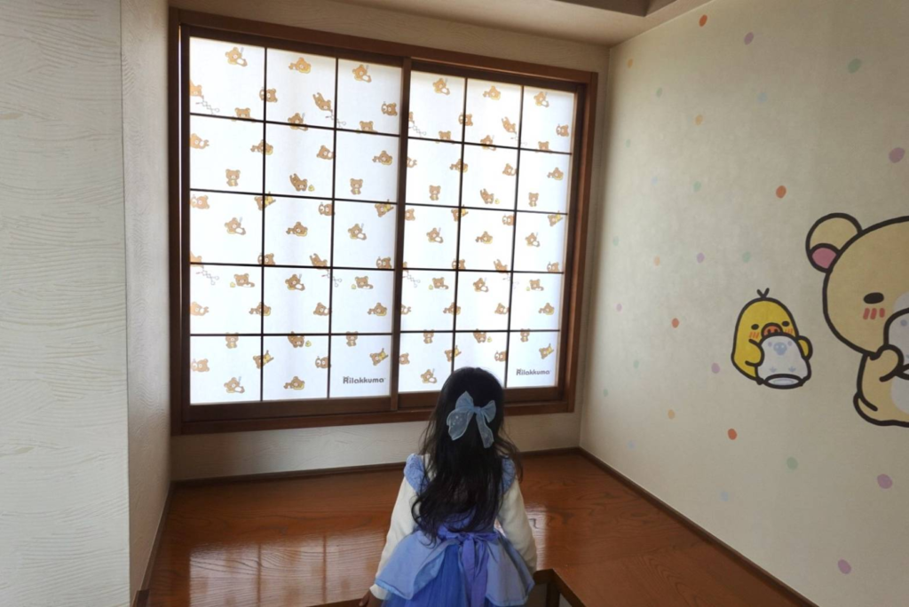 マホロバ・マインズ三浦のリラックマルーム。リラックマのシルエット柄が透ける障子の前で外を眺める子どもの後ろ姿