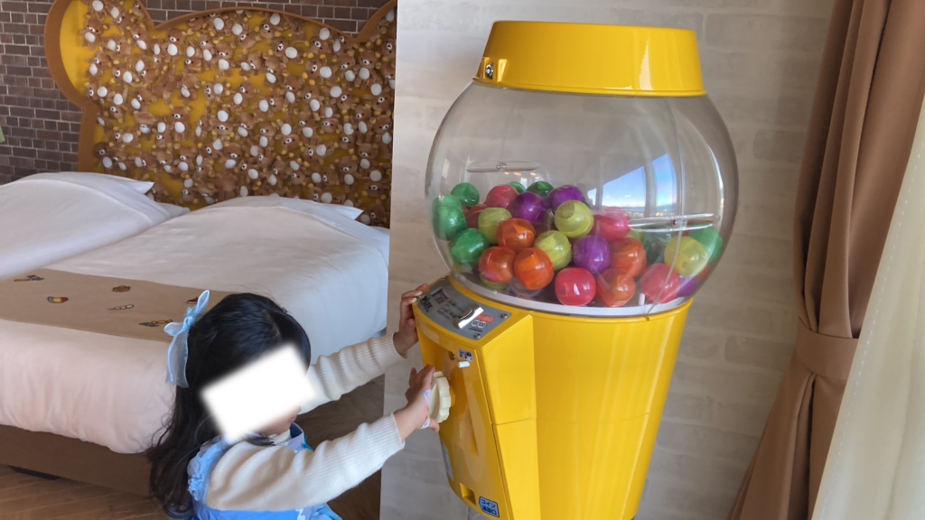 リラックマルーム室内にある黄色い専用ガチャガチャ(ミニカプセルトイ)を回して遊ぶ子ども
