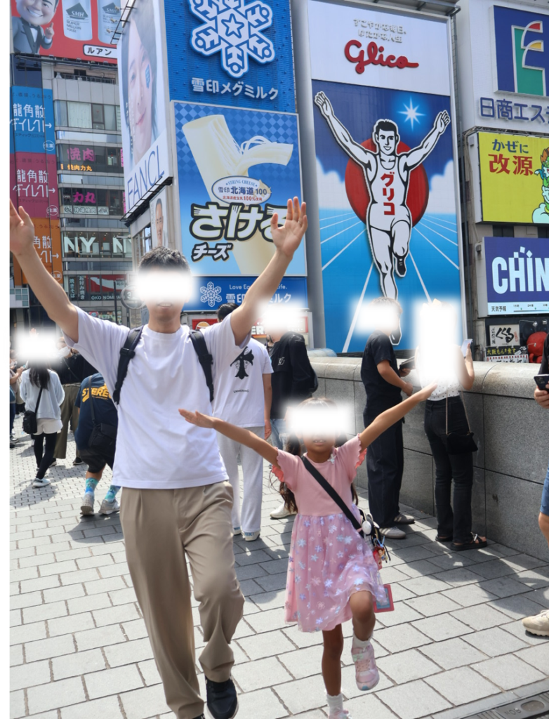 大阪・道頓堀のグリコ看板前でポーズをとる家族の記念写真